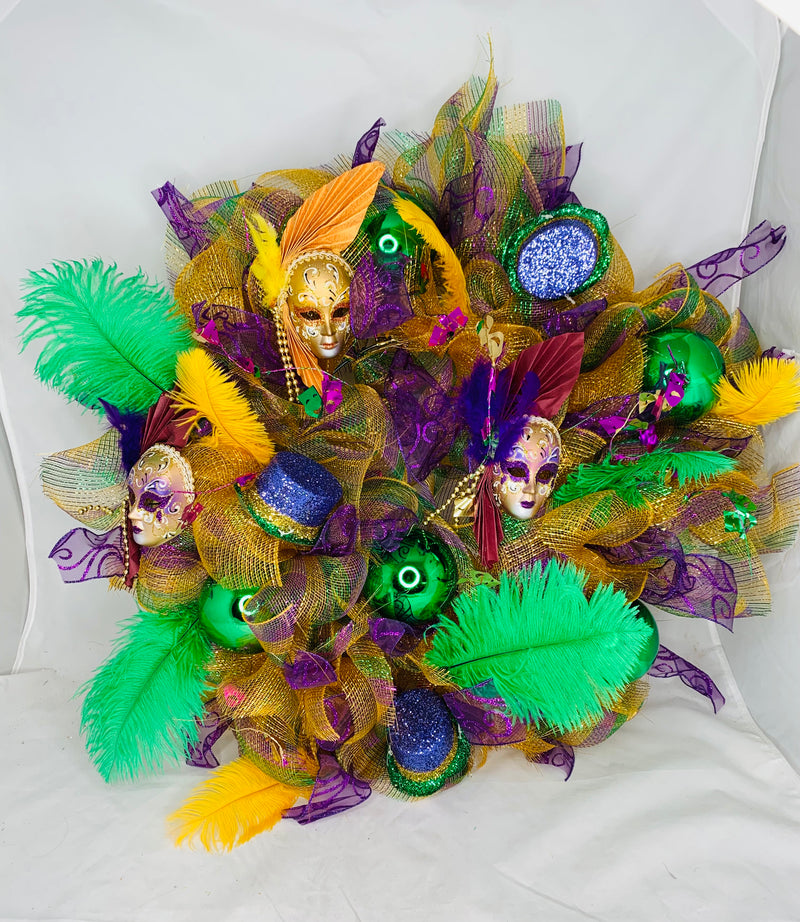 Mardi Gras wreath with small masks, ornaments, green feathers, gold and purple mesh.